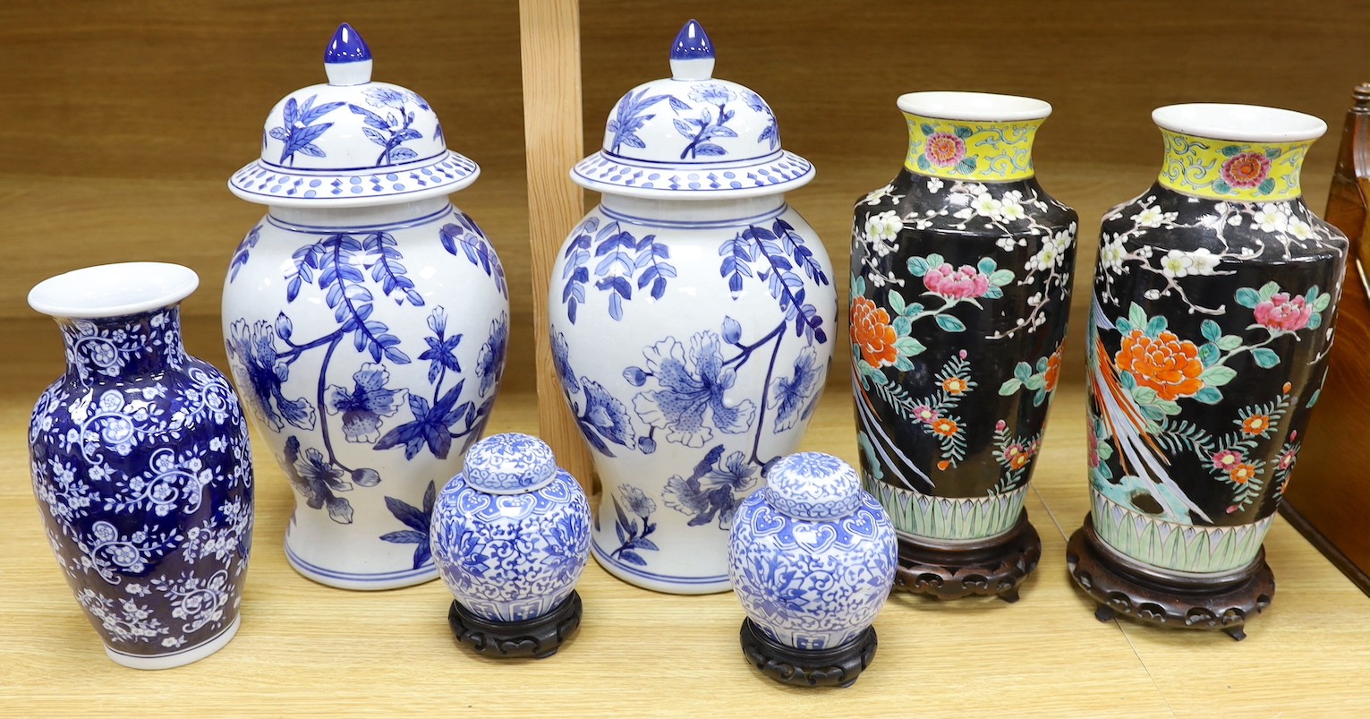 A pair of Japanese black ground vases, a pair of Chinese blue and white vases and covers, a similar pair of jars and a vase, four wood stands. Largest 41cm